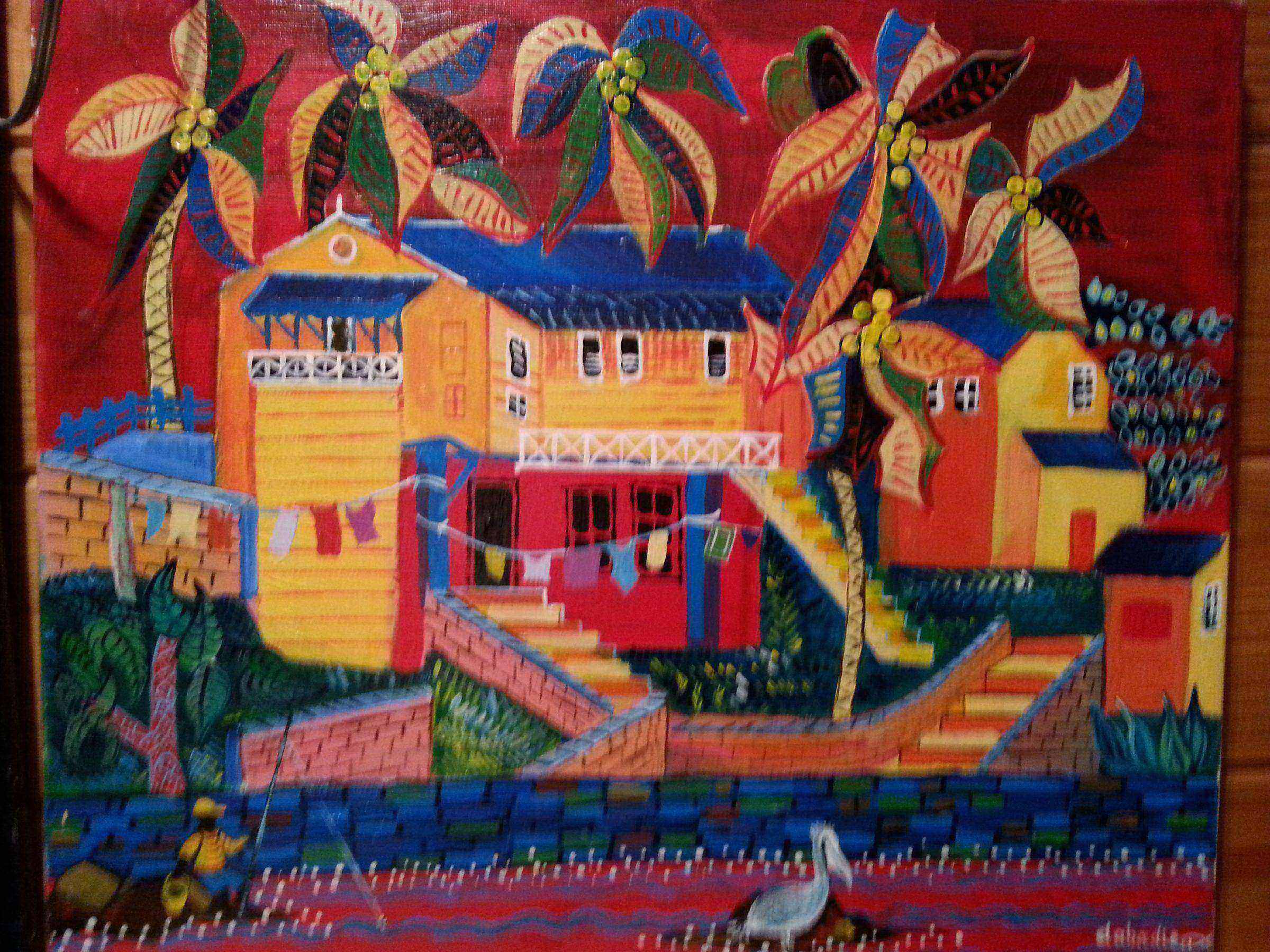 Case créole colorée aux Antilles avec cocotiers linge séchant et pélican au bord de l'eau